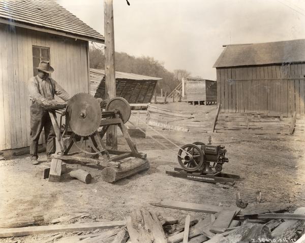 Farmer cutting wood with a circular saw powered by a McCormick-Deering 1 1/2 HP engine.