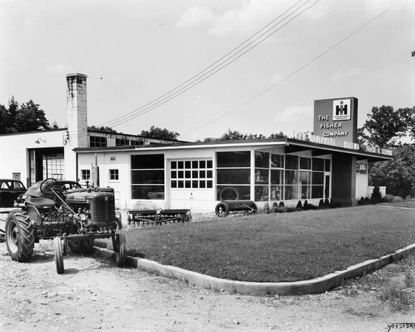 "Prototype" dealership building of the Fisher Company. A Farmall Super A tractor is parked to the left of the building. This "prototype" dealership building was built as part of International Harvester's "Dealer Base of Operations Program." By February of 1948, 386 dealerships had been built on the prototype plan. Another 617 dealerships were under construction or had been built on a modified prototype plan. Eventually over 1800 such dealerships were built worldwide.