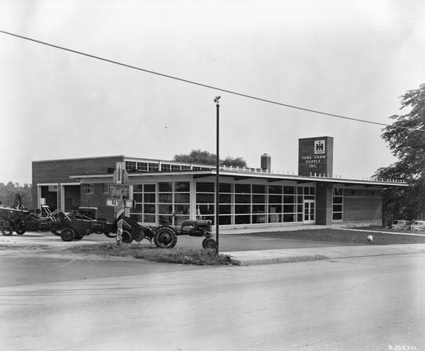 "Prototype" building of York Farm Supply Inc., an International Harvester dealership owned by Charles E. Jacobs. A Farmall Cub tractor is parked in the foreground. This "prototype" dealership building was built as part of International Harvester's "Dealer Base of Operations Program." By February of 1948, 386 dealerships had been built on the prototype plan. Another 617 dealerships were under construction or had been built on a modified prototype plan. Eventually over 1800 such dealerships were built worldwide.