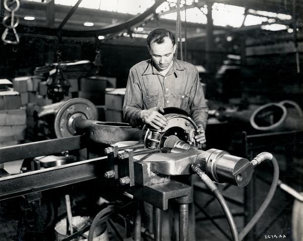 Factory worker assembling brakes on axles for trucks at International Harvester's Fort Wayne Works. The factory was located at Pontiac Street and Bueter Road.