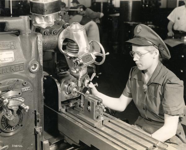 Woman working on a midget mill that cuts spiral grooves and moves at a rate of about 3500 r.p.m. The woman operating this machine was a former drill press operator and had special training in this type of work. The woman is helping to produce aerial torpedoes for the U.S. Military at an International Harvester factory.

