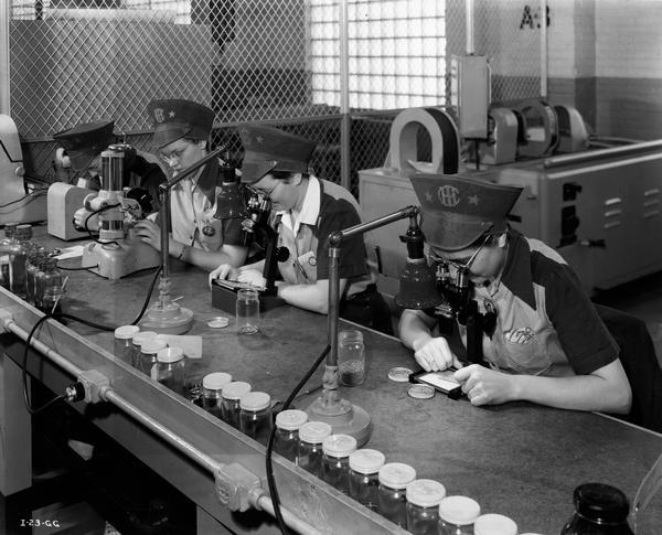 Female factory workers inspect ball bearings at an International Harvester factory. The factory produced aerial torpedoes for the U.S. Military.