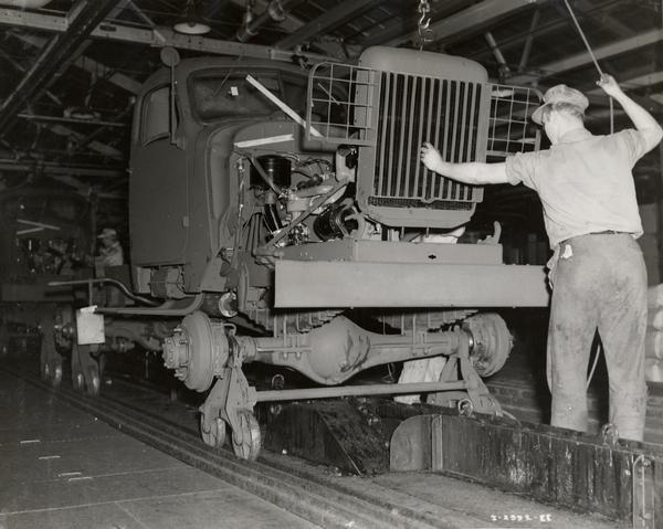 Factory worker attaches the front grill to an International model M-5-6 military truck on the assembly line. The trucks were originally sold to the United States Army, but were later diverted to Russia under the Lend-Lease program.