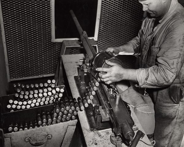 Original caption reads: "A loaded magazine is mounted on a 20mm cannon in one of the test stands at Hazel Park Firing Range." Frederick Viator is the gunner.