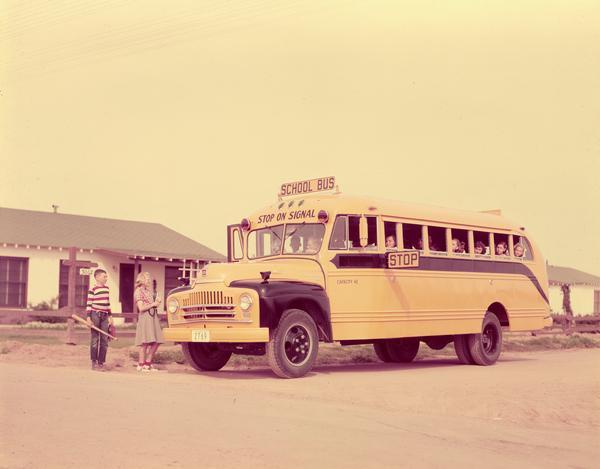 International L-153 schoolmaster bus picking up school children at a residential stop.