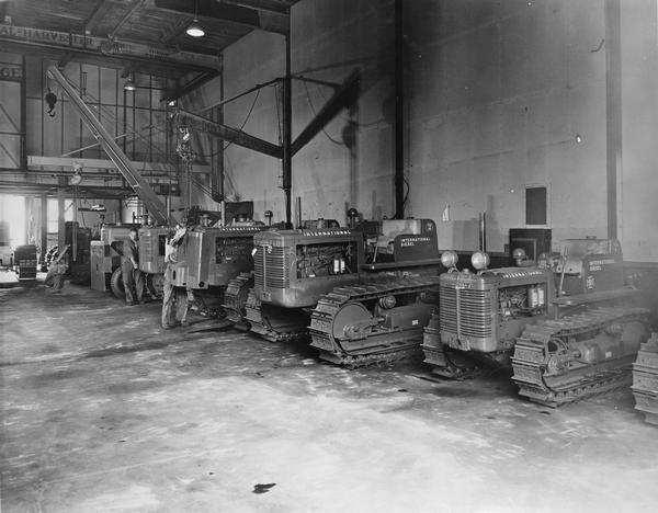Line of International diesel crawler tractors (TracTracTors), including the TD-14 and TD-6 models, parked inside a building (dealership or branch house?).