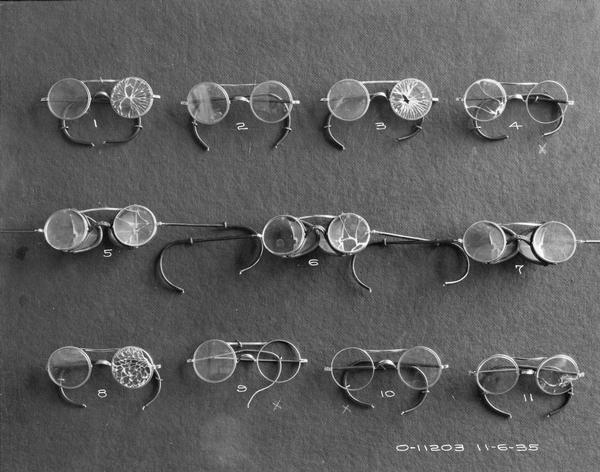Eleven pairs of damaged eyeglasses or spectacles. The eyeglasses may have been worn by workers at International Harvester's Auburn Works (factory), or they may have been tested for safety.