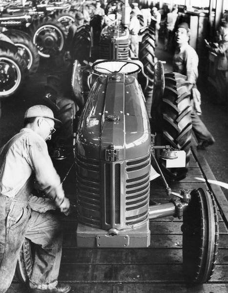 Factory workers making Farmall 300 tractors on an assembly line at International Harvester's Farmall Works.
