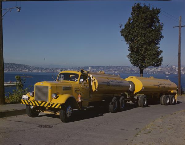 Color photograph of an International LD-400 series tanker truck owned by Eastern Washington Transports, Inc., on a road near the Port of Seattle.