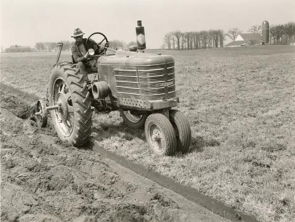 Man plowing a field with an experimental Farmall F-22 tractor.