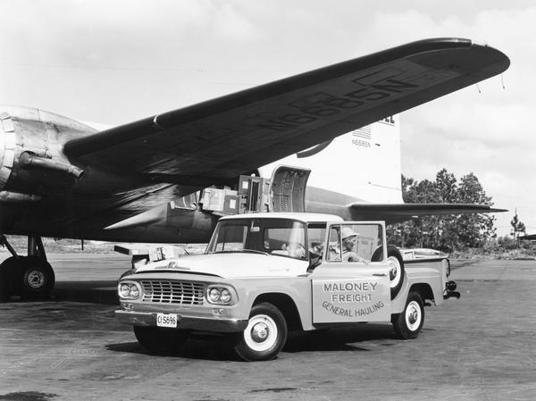Man positioning an International C-110 truck under the wing of an airplane. The truck was owned by Maloney Freight.