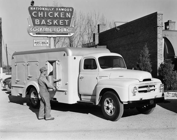 Man delivering goods to the Chicken Basket Cocktail Lounge with an International R-170 refrigerated truck.