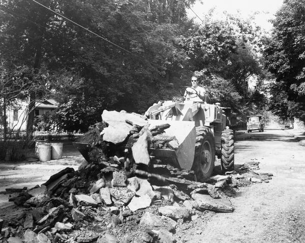 Man working on a residential street with a Hough H-30 front loader. The machine was manufactured by the Frank G. Hough Company.