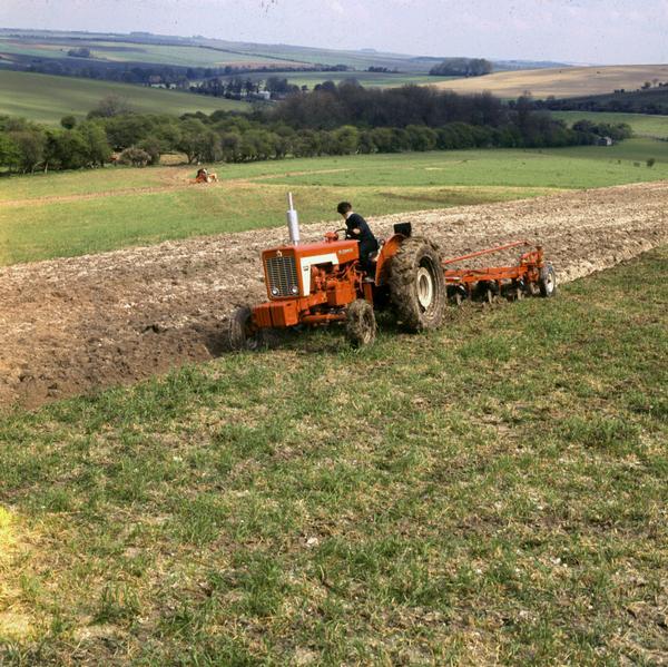 Color photograph of a man plowing a field in Great Britain with a McCormick tractor.