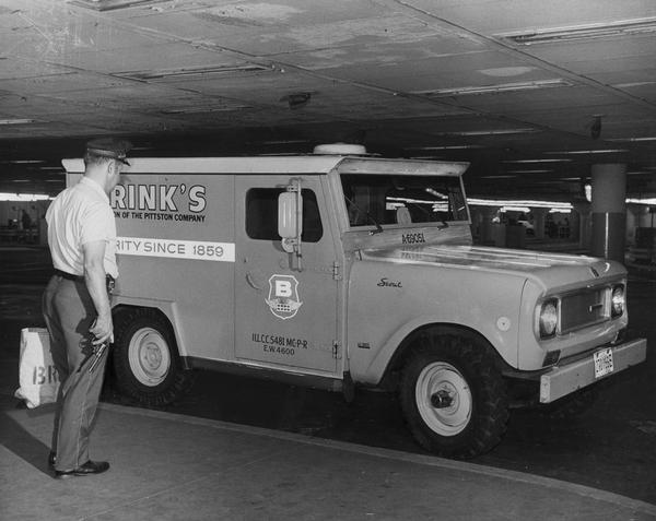 Armed guard approaching an International 4x4 Scout 800A truck built for Brinks, Incorporated.