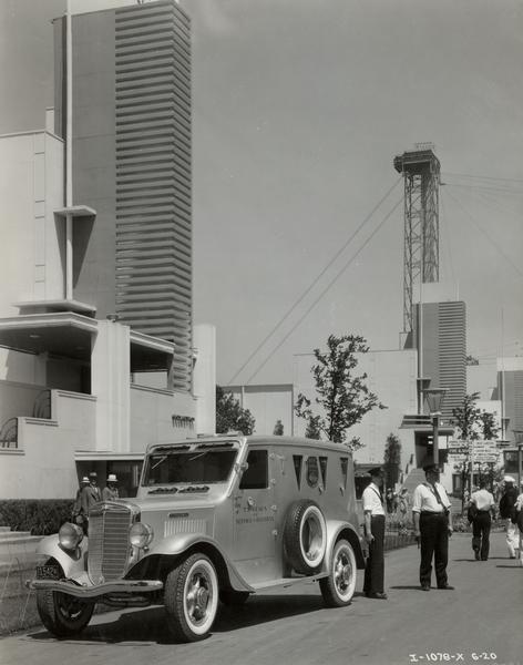 Armed guards with an International armored C series truck owned by the Brinks Express Company parked on a street at Chicago World's Fair "A Century of Progress" exhibition.