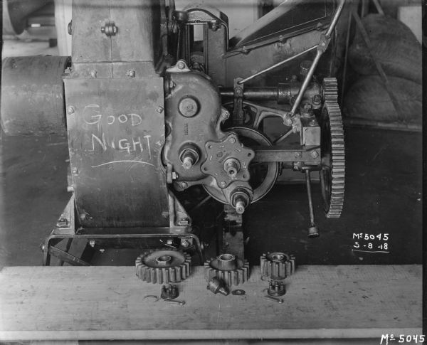 Machinery at International Harvester's McCormick Works. Parts are layed out in front of the machine, and "Good Night" is written on the side in chalk.