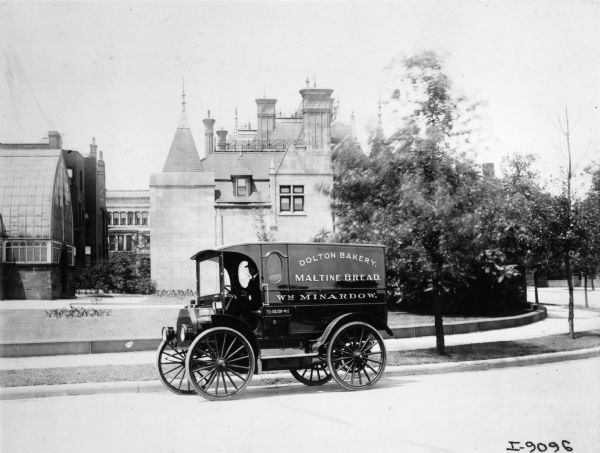 A man is driving a 1909 International Auto Wagon with an enclosed body belonging to Dolton Bakery.