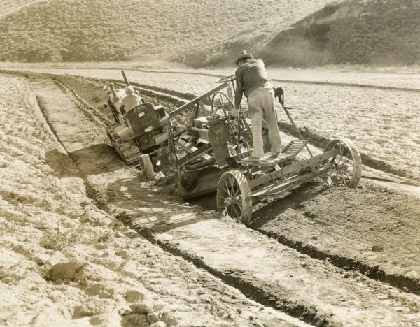 McCormick-Deering TracTractor (crawler tractor) pulling what appears to be a grader through a field.