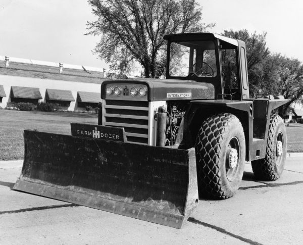 International Harvester tractor with a mounted dozer blade. The blade bears the IH logo and the words "farm dozer."