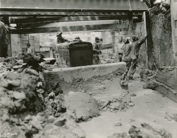 Men using a McCormick-Deering TracTractor (crawler tractor) on a construction project, possibly a tunnel.