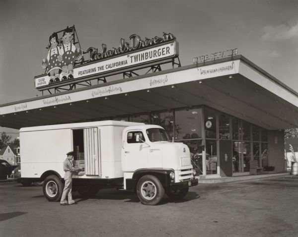 A deliveryman unloading crates of cottage cheese from his International LC-180 International truck with refrigerated body outside Richards Drive-In.