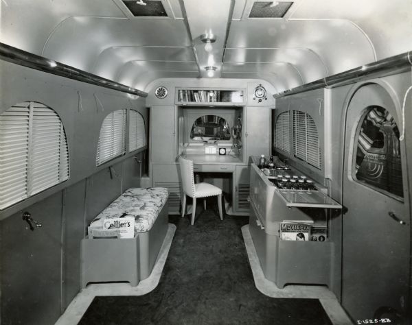 Interior of an International "Jungle Yacht," including a desk and chair, a bookshelf, a bench, a sink, and reading materials such as movie magazines and books. International Harvester produced this truck for one of explorer Commander Attilio Gatti's expeditions to the African Congo.