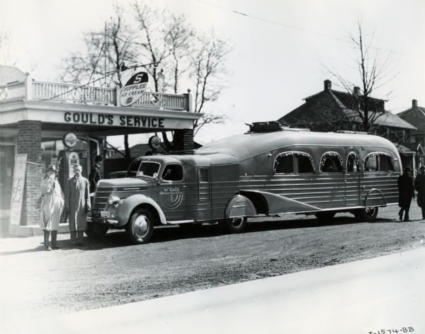 International "Jungle Yacht" parked at "Gould's" service station on the way from an International Harvester factory to New York City. Explorer Attilio Gatti is standing in front of the truck (far left). The truck was used on the Tenth Gatti African Expedition. The "Jungle Yachts" were specially produced by Inernational Harvester for Commander Attilio Gatti's expeditions to the African Congo.