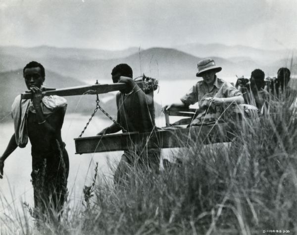 Mrs. Attilio Gatti carried by four Congolese men during her husband's expedition to the African Congo. The expedition was sponsored by the International Harvester Company.