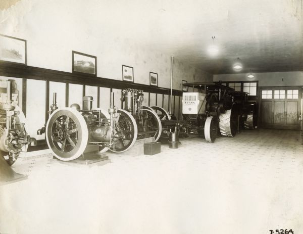 Showroom, most likely of an International Harvester dealership, with stationary engines and a Titan tractor.