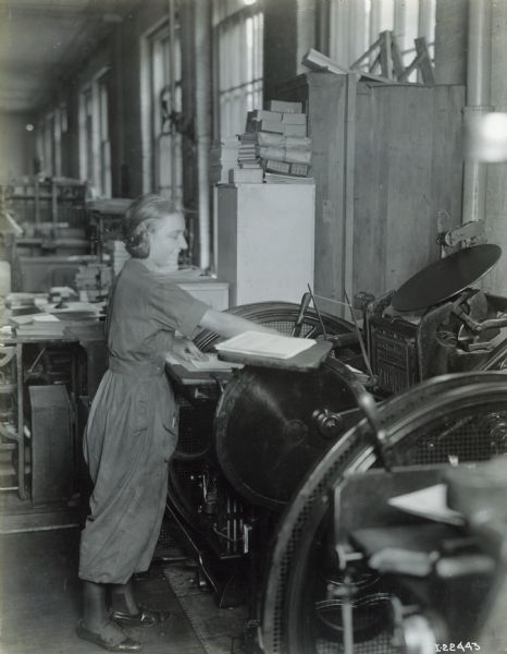 Female worker operating machinery at Harvester Press, International Harvester's in-house print shop.