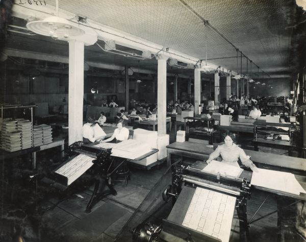 Women printing large sheets of paper at Harvester Press, International Harvester's in-house print shop.