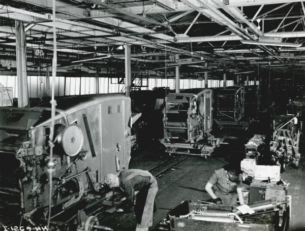 Elevated view of men and women working on a combine (harvester-thresher) assembly line at International Harvester's East Moline Works.