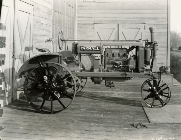 Farmall Regular tractor on a wooden deck attached to a wooden building. The building may be a warehouse.