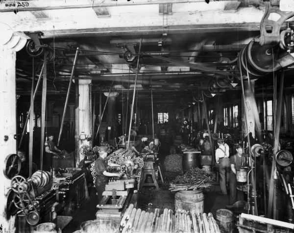 Slightly elevated view of factory workers working parts, most likely at the McCormick Reaper Works. After 1902, the factory became International Harvester's McCormick Works.