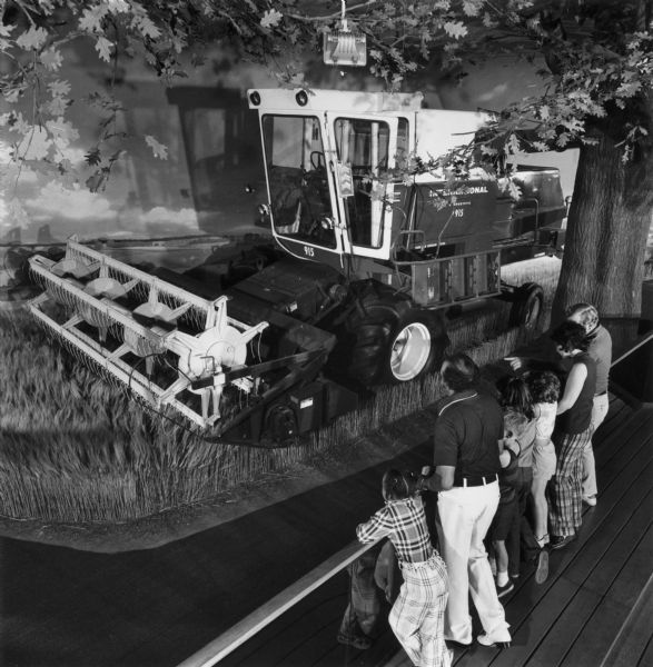 Elevated view of visitors examining a 915 hydrostatic combine (harvester-thresher) in the International Harvester exhibit at the Museum of Science and Industry.