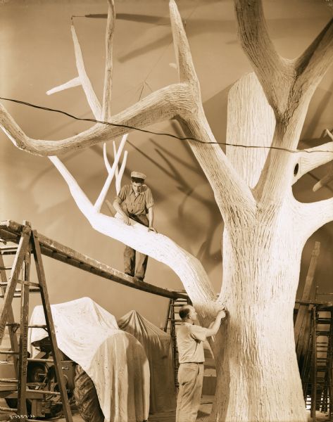 Craftsmen working on a tree in the model farmyard of the Harvester Farm exhibit at the Museum of Science and Industry.