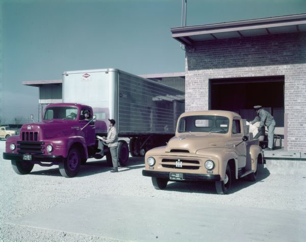 Color photograph of International R-195 And R-120 trucks and truck drivers at a loading dock.