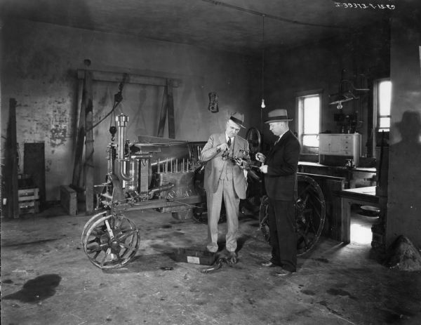 Two men examine a tractor part in a workshop at the International Harvester dealership of O.T. Kercheval.