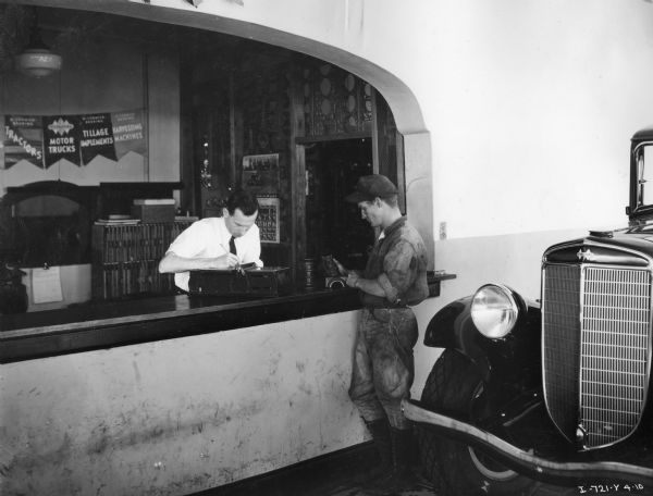 Customer and salesman at the sales counter of the Orange Belt Truck & Tractor Company, an International Harvester dealership. An International truck is in the foreground.