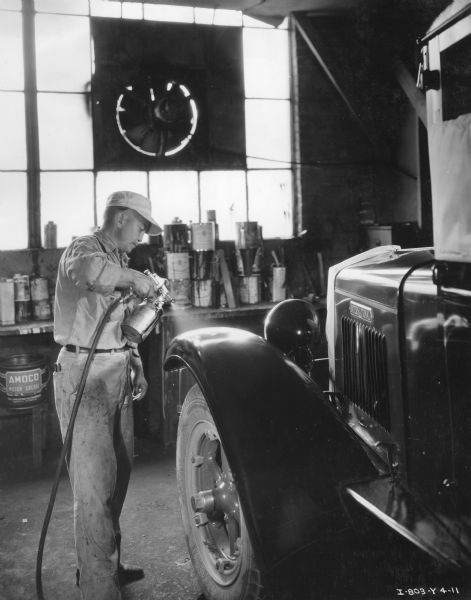 Eddie Pearce, foreman of the paint shop at the Orange State Motor Company, works on an International truck.