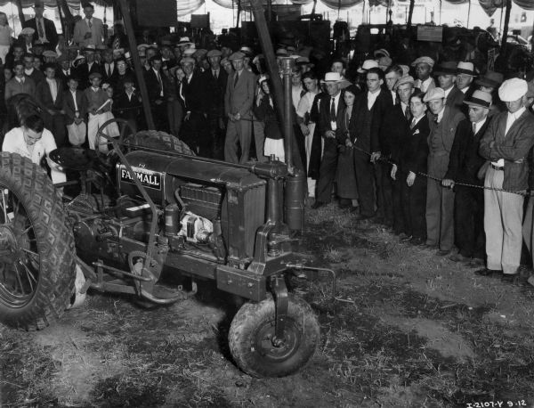 A crowd of spectators looks at a McCormick Farmall tractor on display at the Wisconsin State Fair. The tractor is an F-12.