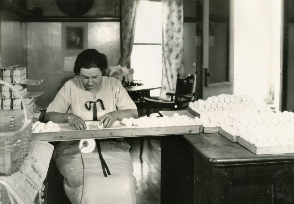 A seated woman candling eggs at Holden Farm.