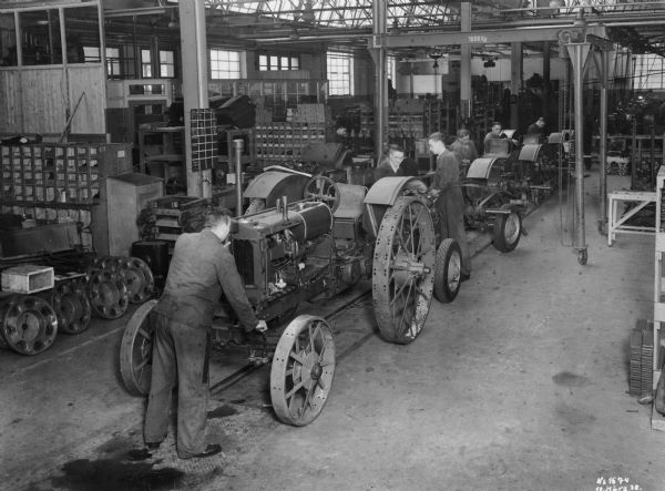 Men are working on a tractor assembly line at International Harvester's Neuss Works (factory) in Germany.