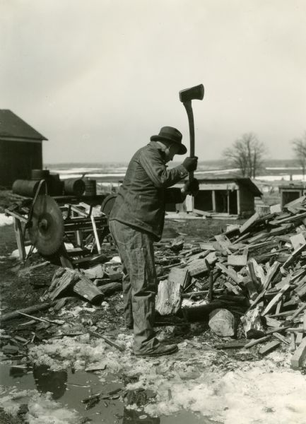 A man demonstrates the farm hazard of chopping wood.