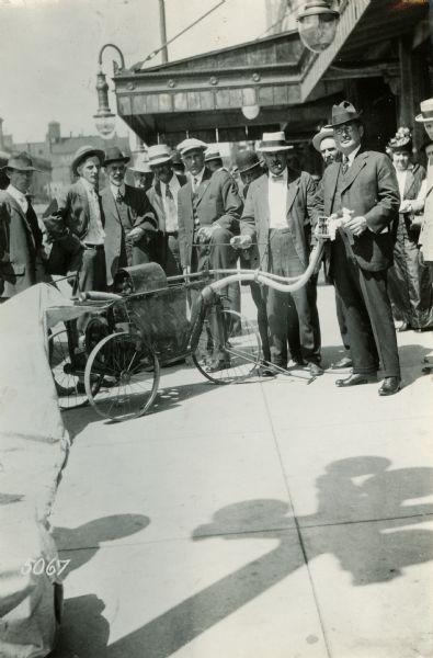 Men gathered outdoors around a cotton picking machine exhibited at the National Implement and Vehicle Association Meeting.