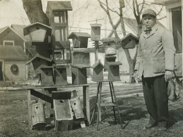 J.M. Eheim posing outdoors with multiple birdhouses.