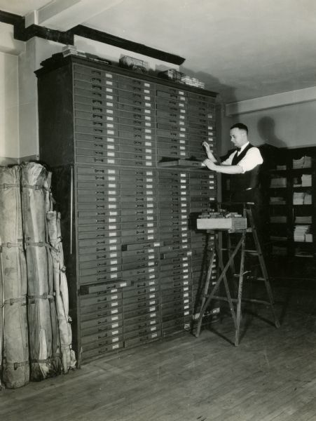 Mr. Priestman standing on a ladder, looking through the "electro file."