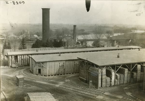 Elevated view of the lumberyard at International Harvester's Chatham Works in Canada. Railroad tracks are leading to the storage facilities are in the foreground.