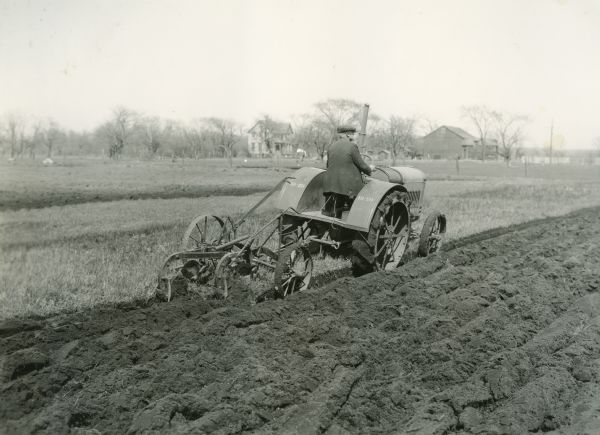 A farmer using a McCormick-Deering 10-20 tractor to plow a field on the J.W. Esch farm.